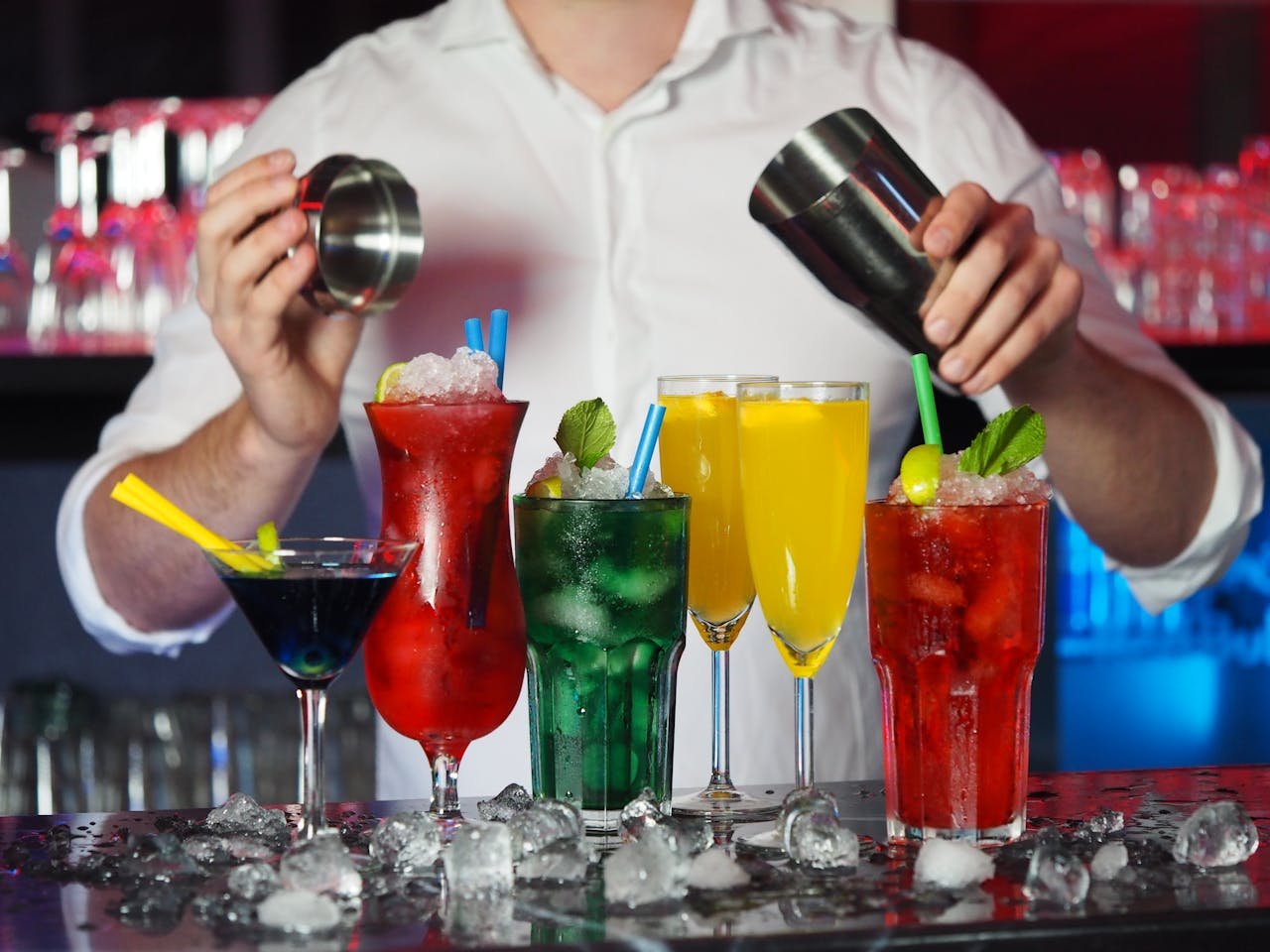 Vibrant assortment of cocktails prepared by a bartender in a dynamic bar setting.